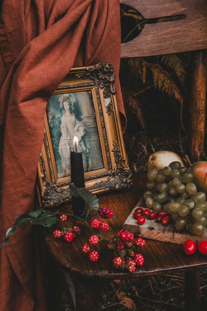 Lumanare neagra arzand, in decor cu tablou, plante, fructe